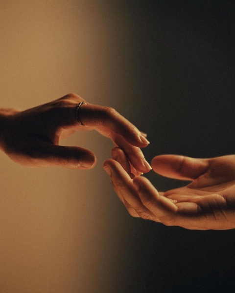 Two hands reaching towards each other, almost touching