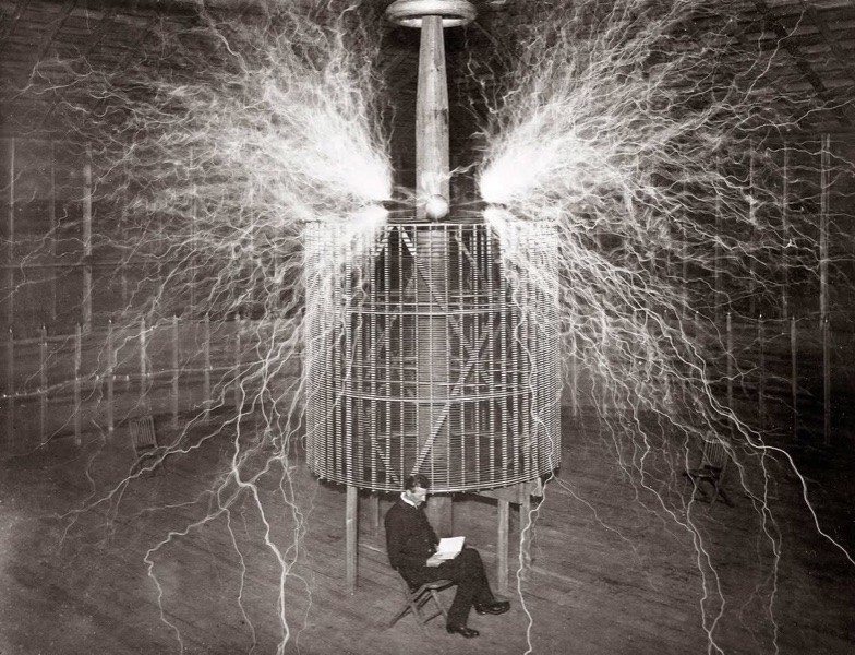 Nikola Tesla reading in his Colorado Springs laboratory as sparks arc overhead, 1899